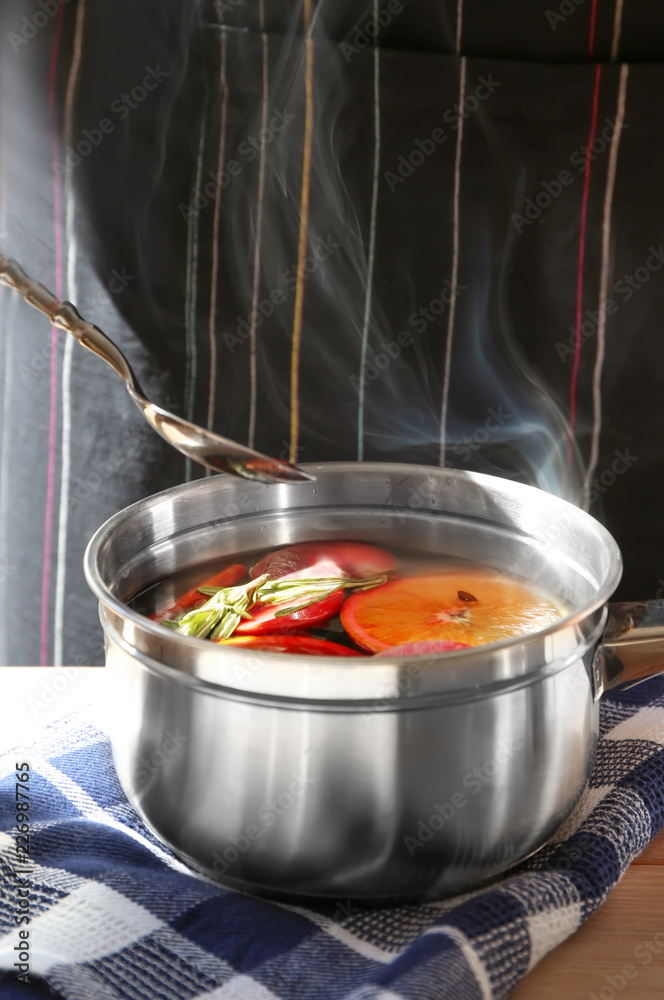 Woman preparing mulled wine at table, closeup