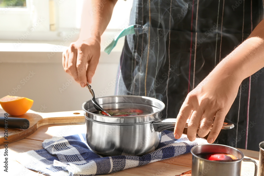 Woman preparing mulled wine at table