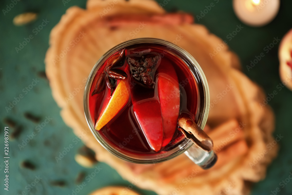 Glass cup of delicious mulled wine on color table, closeup