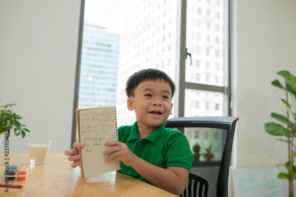 Head shot Portrait of happy asian cute child doing homework with smile face at home .