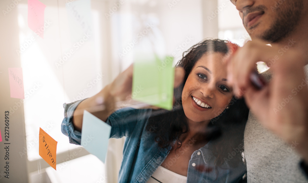 Business colleagues discussing work on a glass board in offic