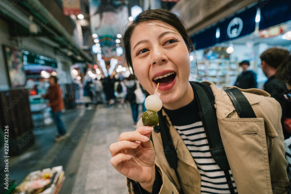 旅行者愉快地尝试日本街头美食