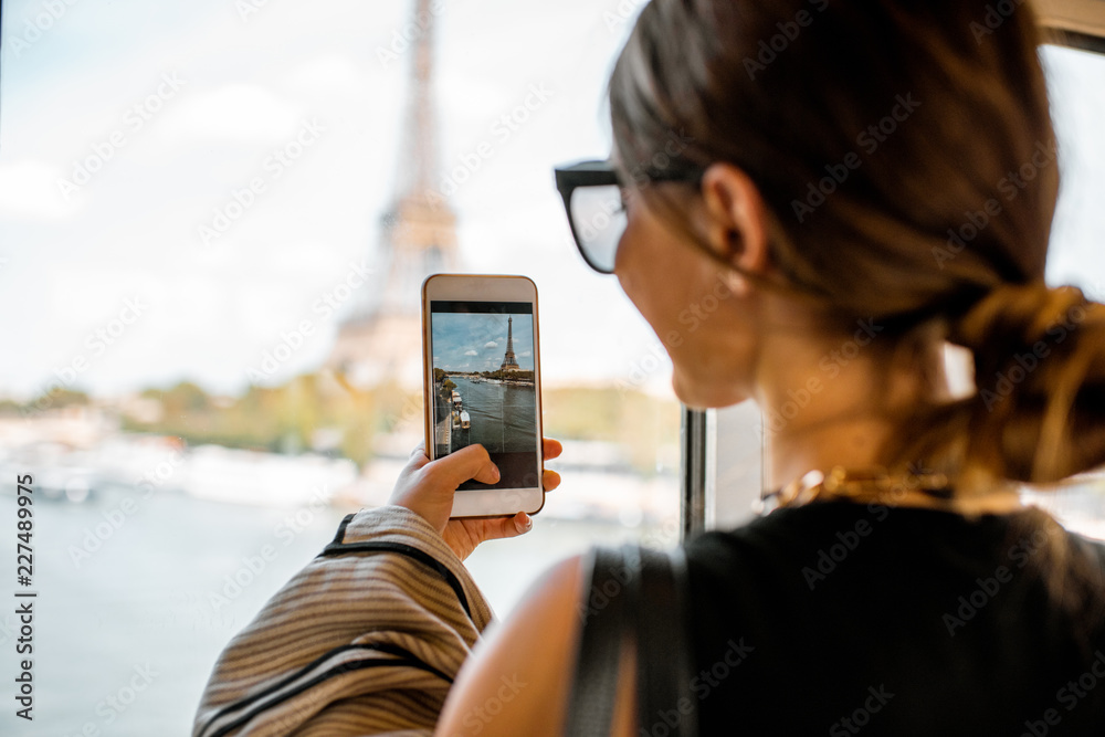 Young woman photographing with smartphone Eiffel tower from the subway train in Paris. Image focused