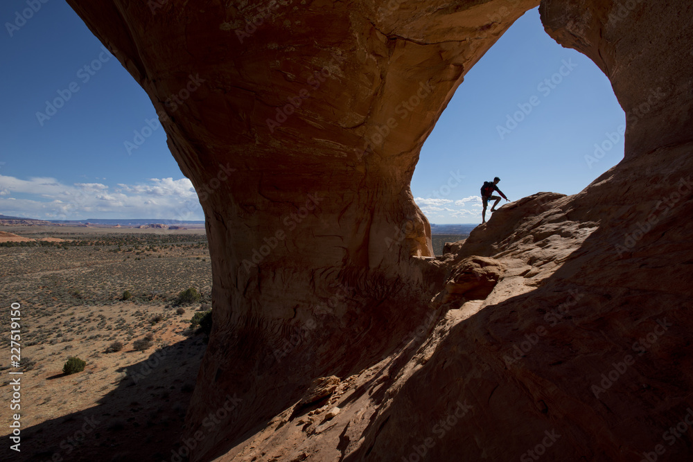 Silhouette hiker climbing rock formation on sunny day