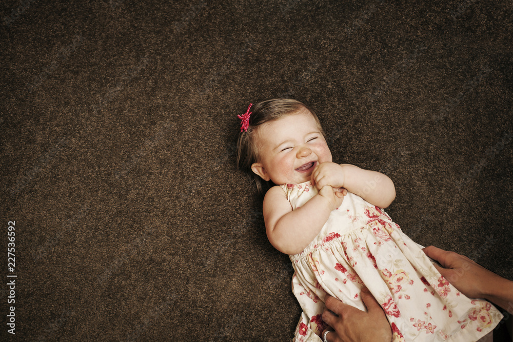 Overhead view of hands holding happy baby on floor