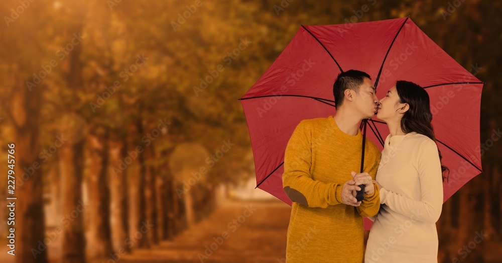 Autumn couple under umbrella in front of trees