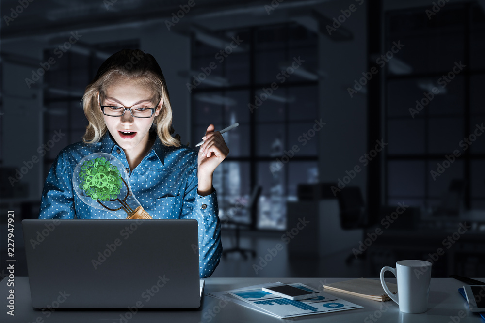 Attractive blonde wearing glasses in dark office using laptop. M