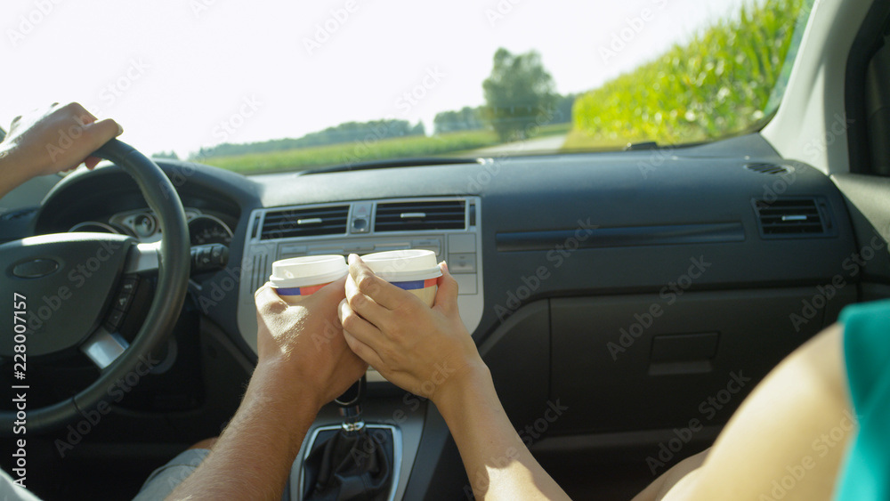 CLOSE UP: Unrecognizable couple toasts in the car with disposable coffee cups