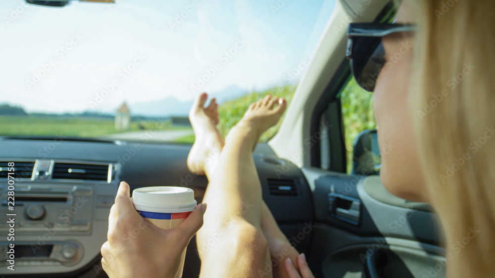 特写：一位年轻女士在一次夏季公路旅行中拿着一杯外卖咖啡。