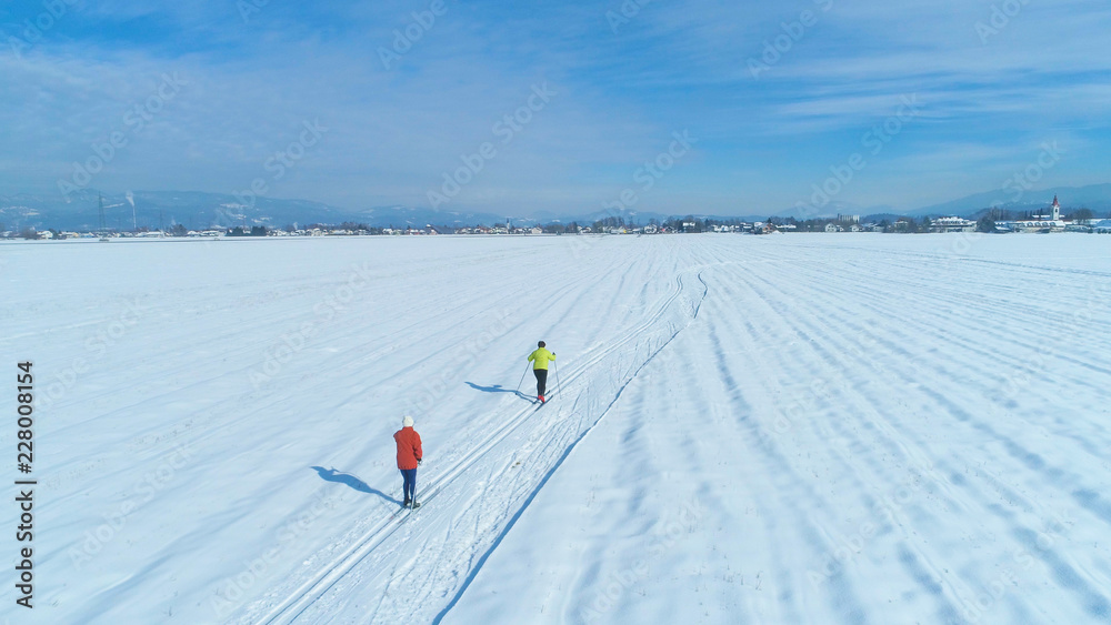 空中飞航：在一个阳光明媚的冬日，不可辨认的活跃女子在越野滑雪。