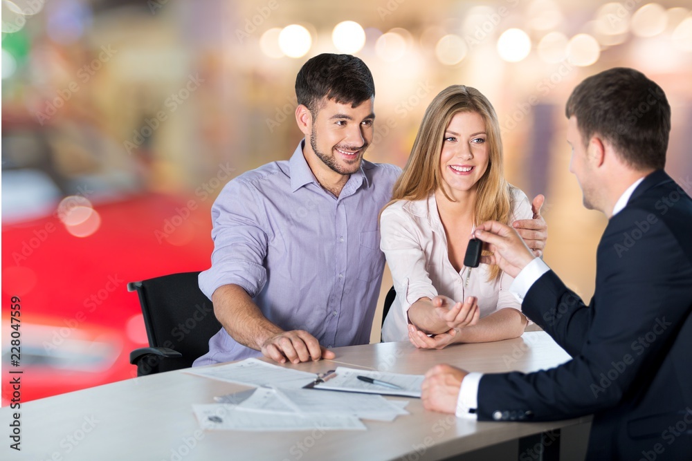 Happy couple with car dealer in auto