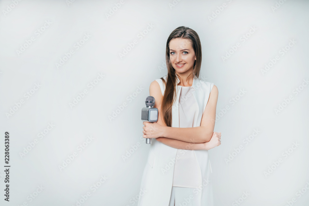 pretty presenter holds in her hand a microphone on a white background in the studio. Beautiful girl 