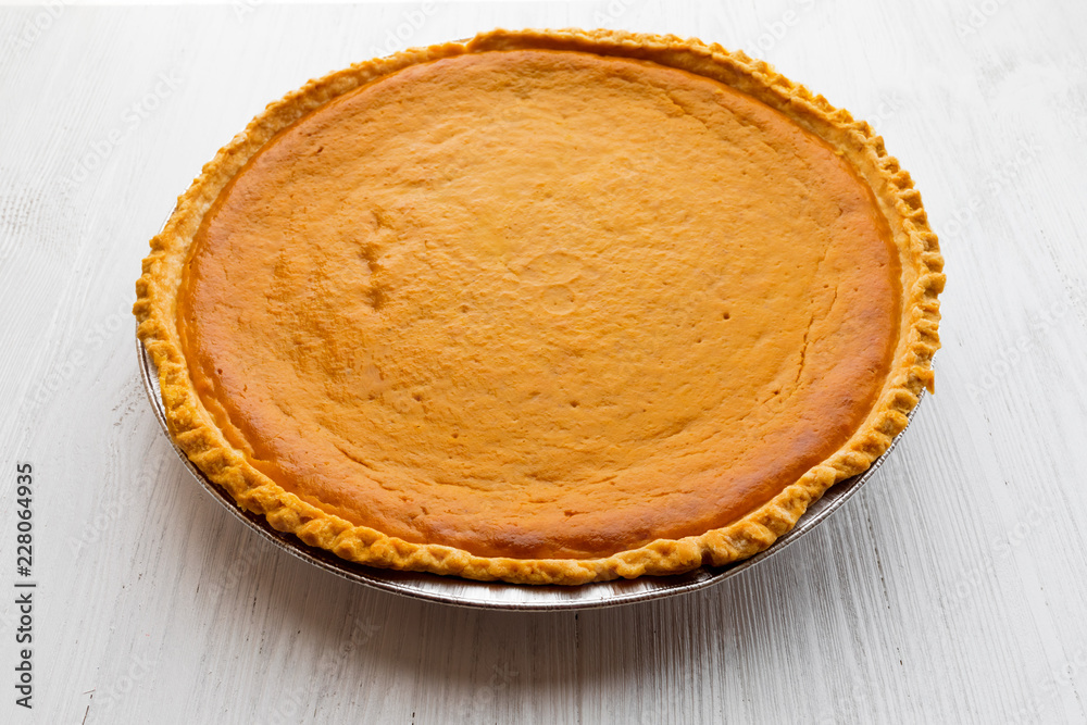 Fresh baked pumpkin pie over white wooden background