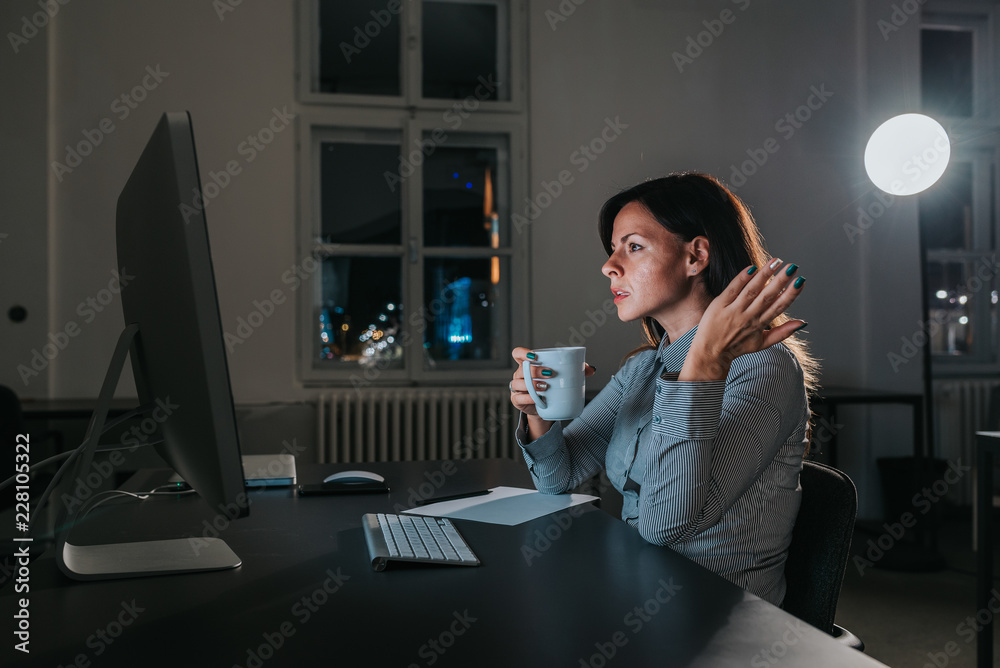 Angry businesswoman looking at computer screen at night. Side view.