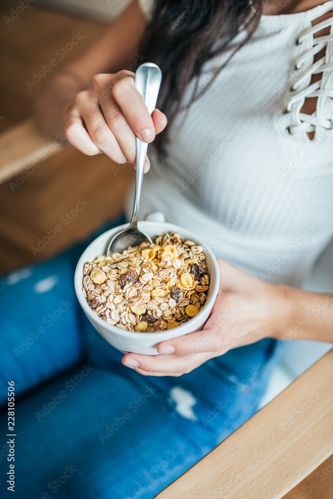 Top view of young woman eating muesli.