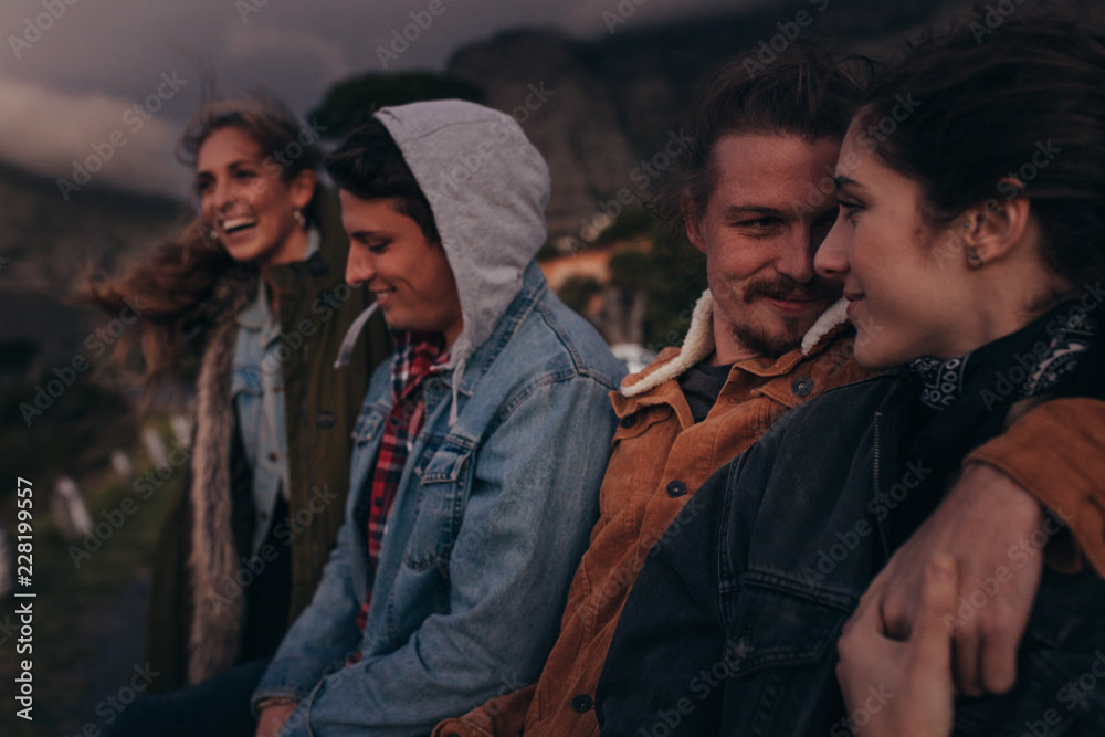 Friends standing on a highway on top of a hill at dusk