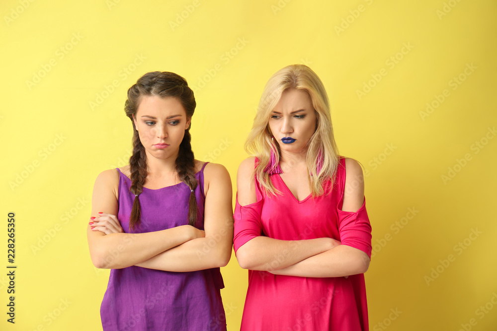 Portrait of beautiful offended women on color background