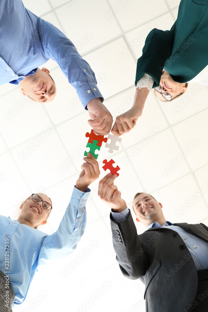 Business team with pieces of puzzle in office, bottom view