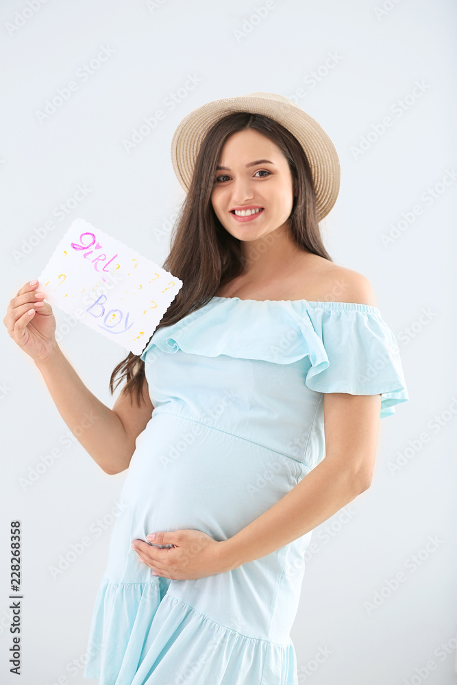 Beautiful pregnant woman holding paper with text BOY? GIRL?