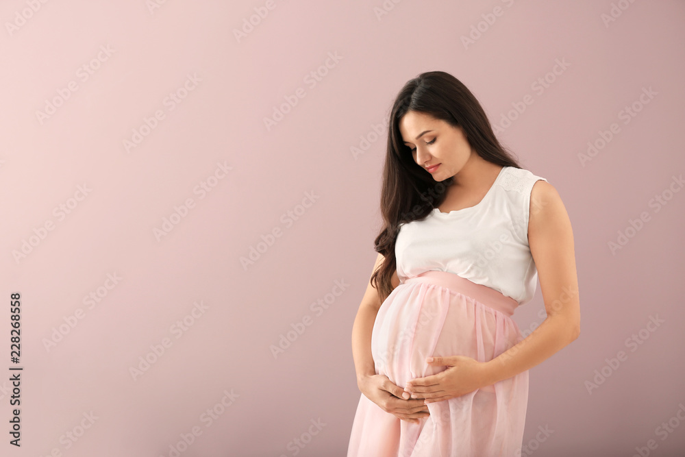 Beautiful pregnant woman on color background