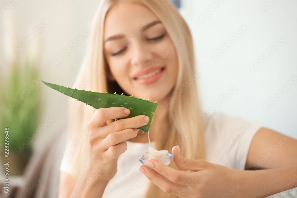 美丽的年轻女子在家中使用芦荟提取物面霜