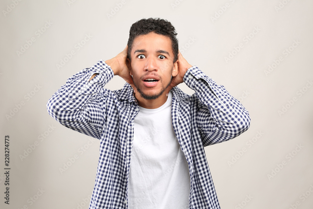 Portrait of scared African-American man on light background