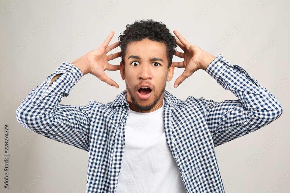 Portrait of emotional African-American man on light background