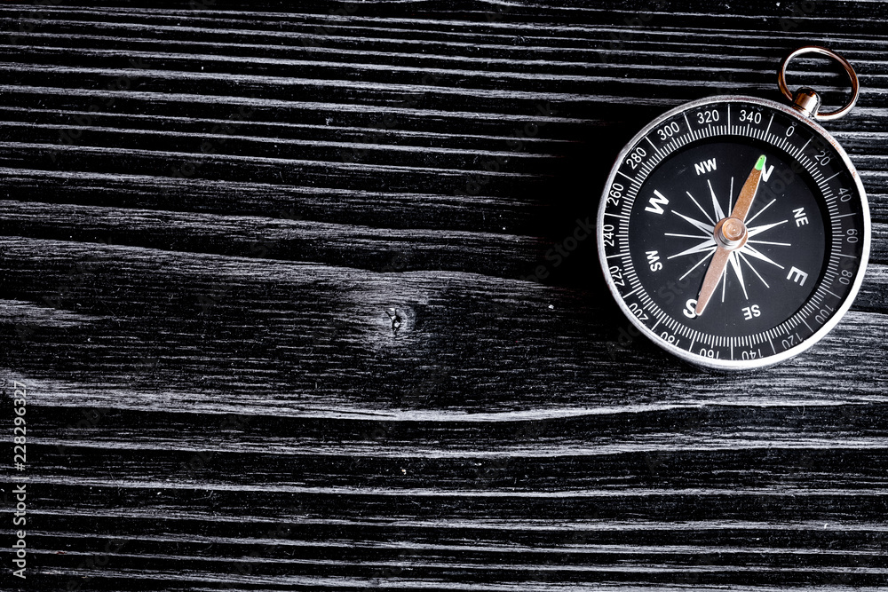 compass on dark wooden background concept direction motion top v