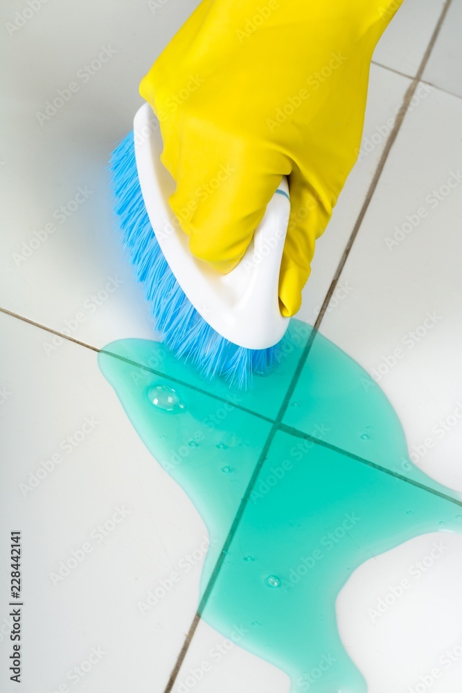 Hand in Rubber Glove Holding a Brush and Cleaning Tiles