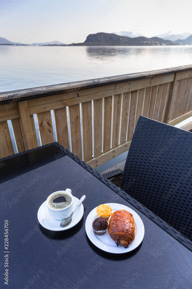 Coffee cup and croissant on the table by the sea