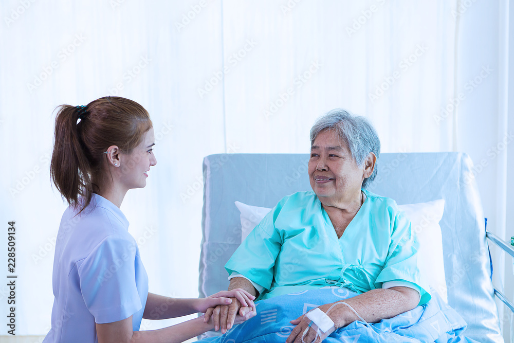 Nurse reassuring her patient on bed in hospital / healthcare medical concept. copy space