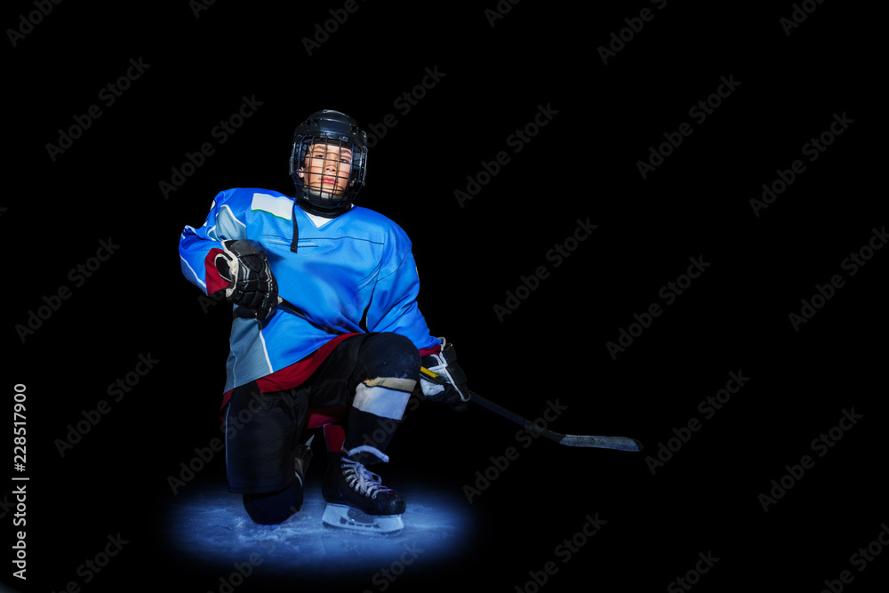 Young hockey player spotlighted on dark background