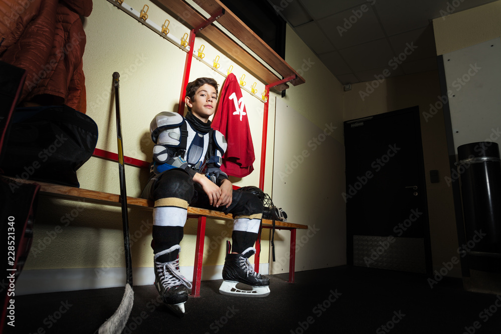 Boy sitting on the bench in hockey dressing room