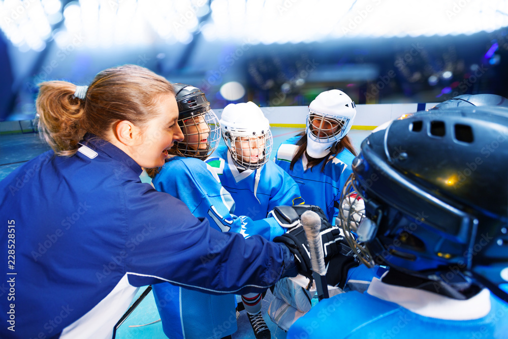 Coach and hockey players putting hands in huddle