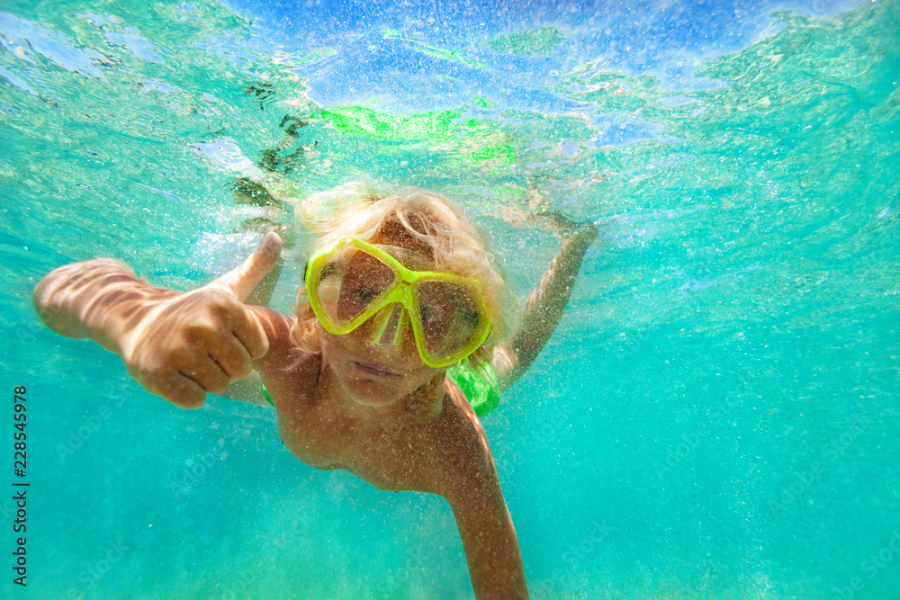 Boy giving thumb up while swimming underwater