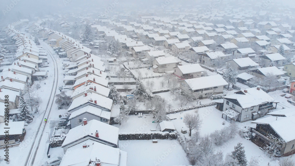 AERIAL: Flying above the white snowy backyards on a spectacular winter day.