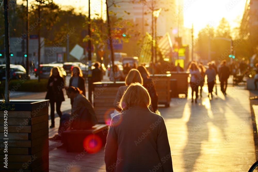 Street scene of people walking during the sunset on street.  