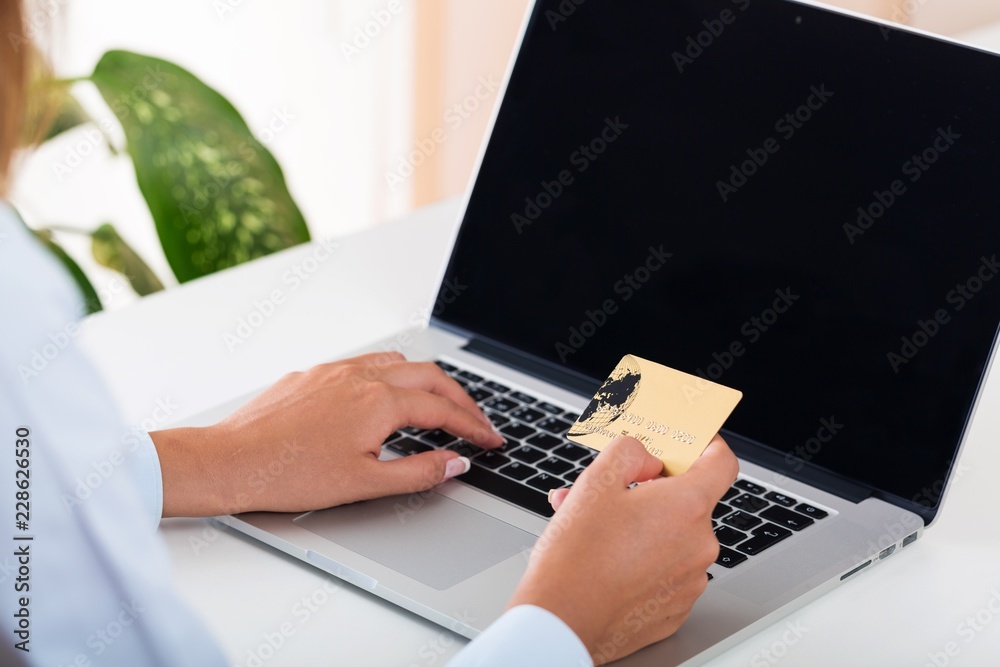 Closeup of a Woman Typing on a Laptop and Holding a Credit Card