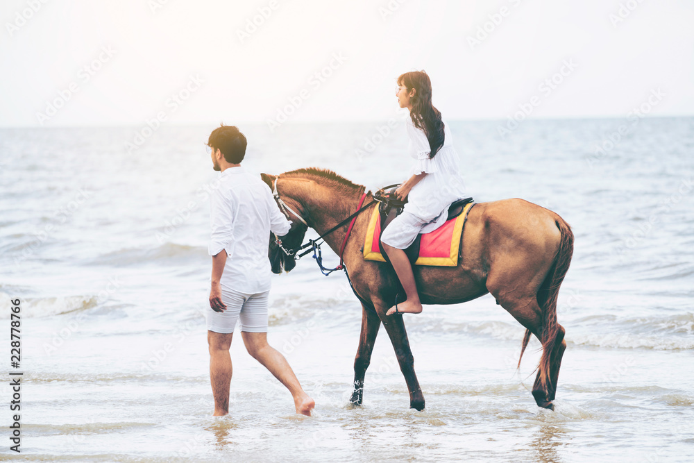 年轻夫妇在热带海滩上骑马。