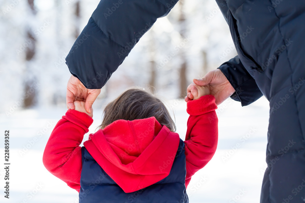 Toddler boy playing in the snow with his mother