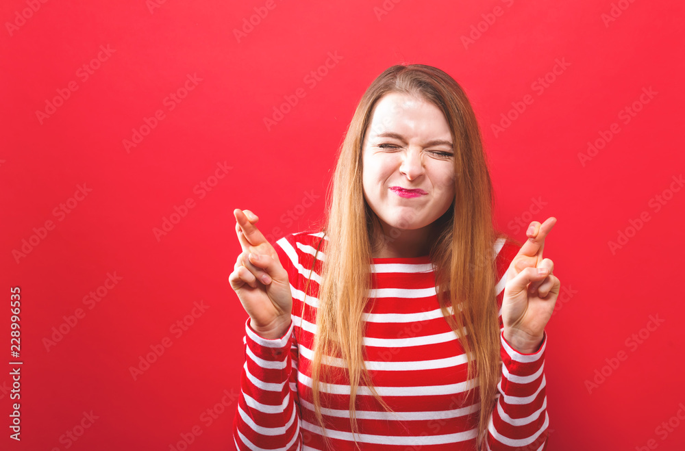 Young woman crossing her fingers and wishing for good luck