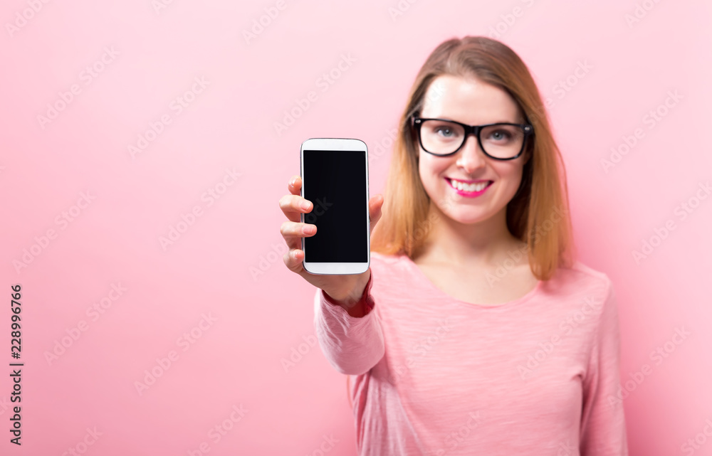 Young woman holding out a cellphone in her hand