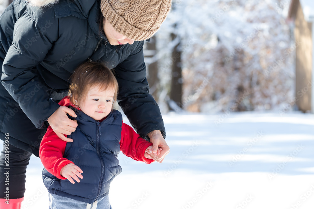 蹒跚学步的男孩和妈妈在雪地里玩耍