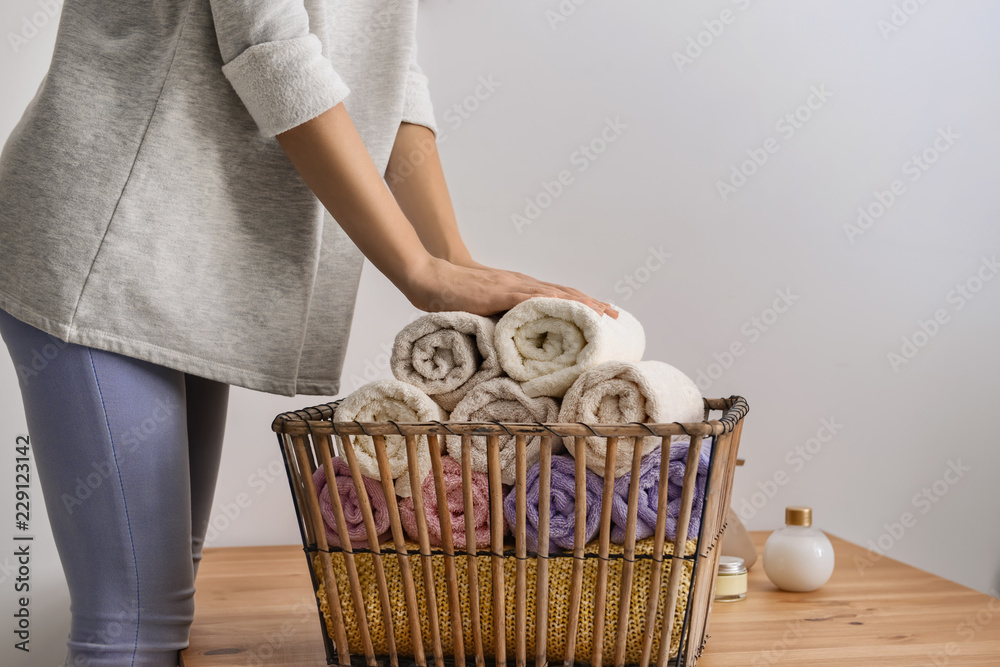 女人在木桌旁把干净的软毛巾折叠到篮子里