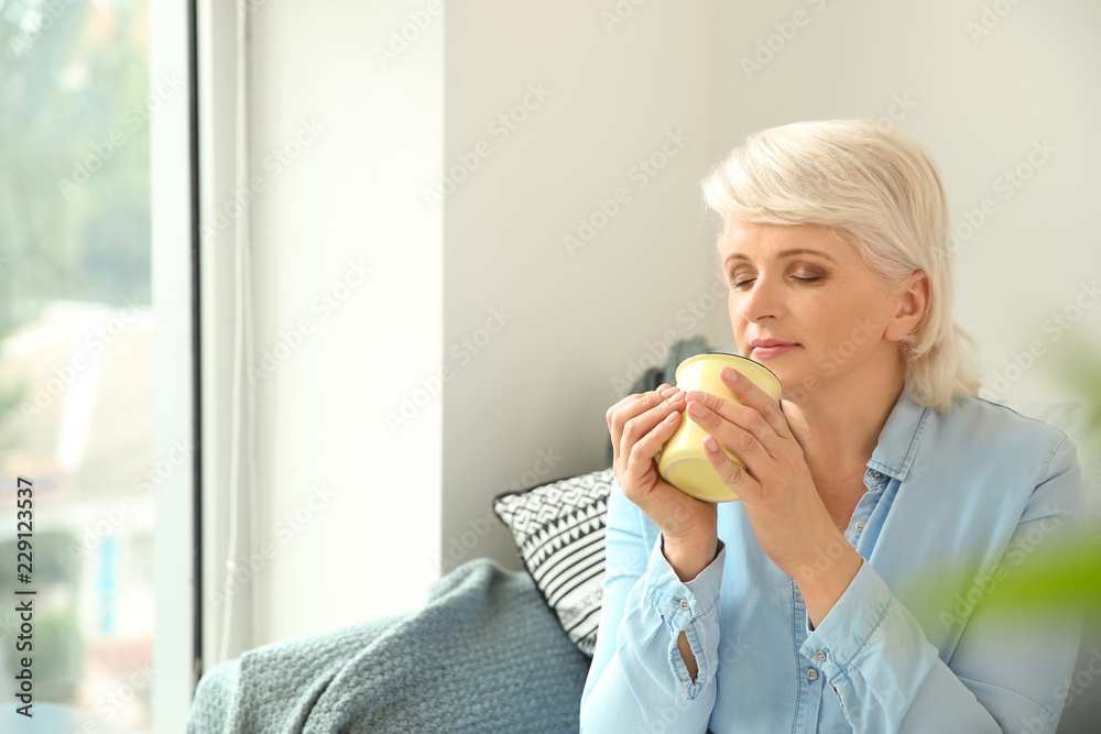 Beautiful mature woman drinking coffee at home