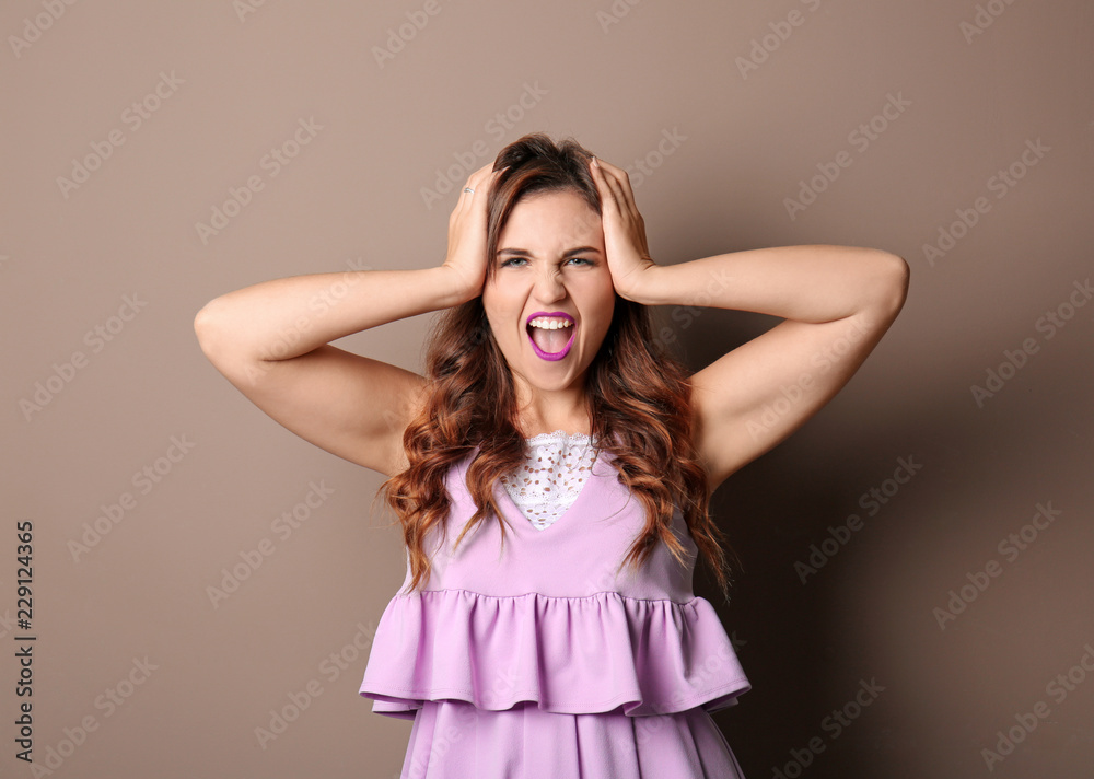 Portrait of aggressive young woman on color background