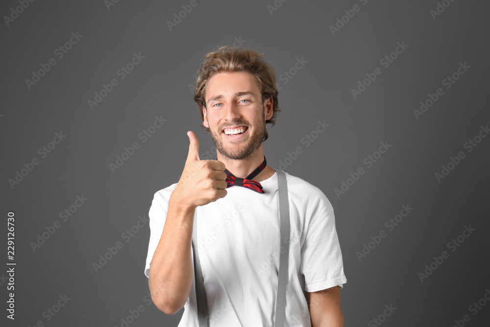 Portrait of handsome man showing thumb-up on grey background