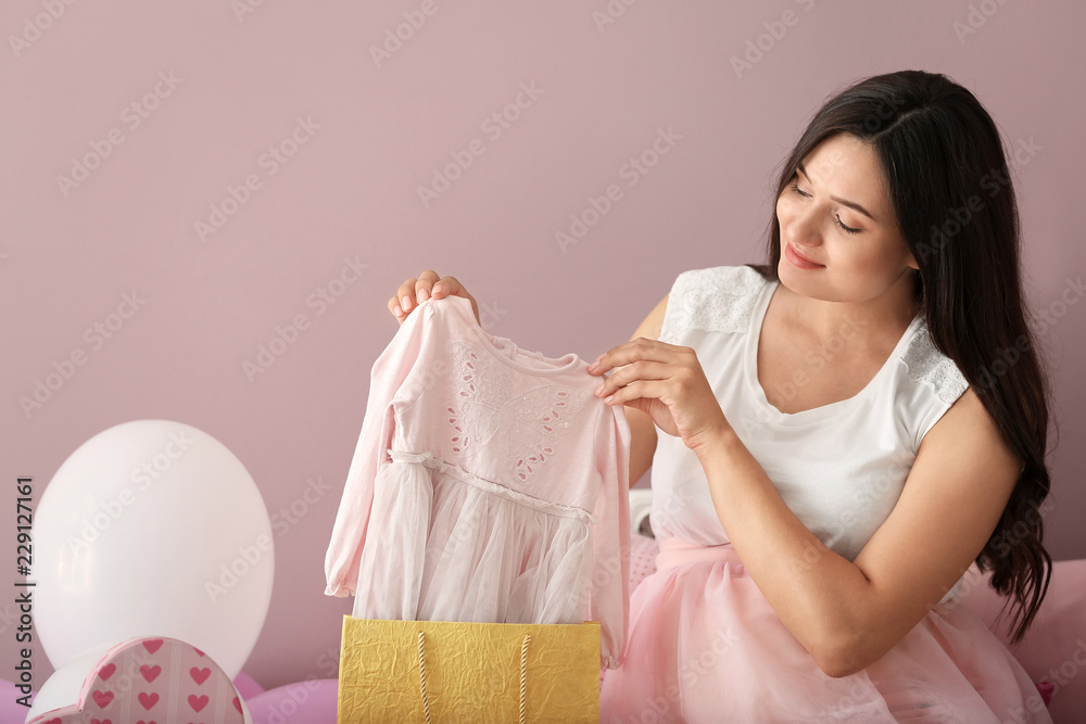 Beautiful pregnant woman with baby shower gifts at home