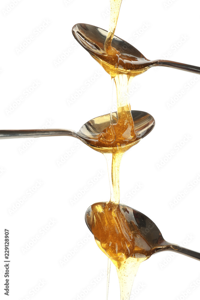 Metal spoons with honey on white background