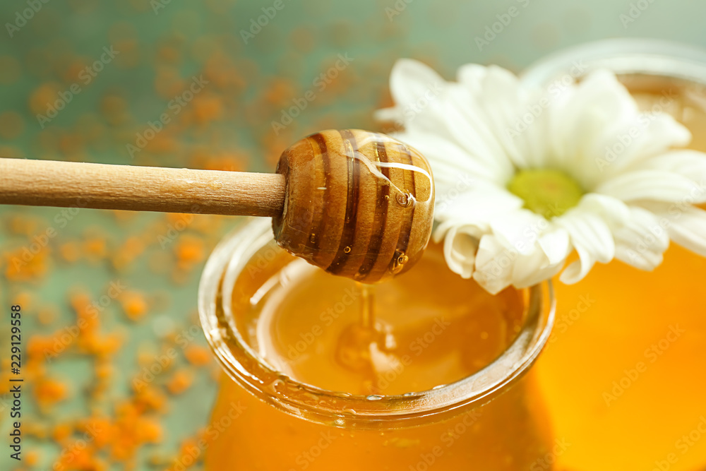 Jar of honey and wooden dipper, closeup